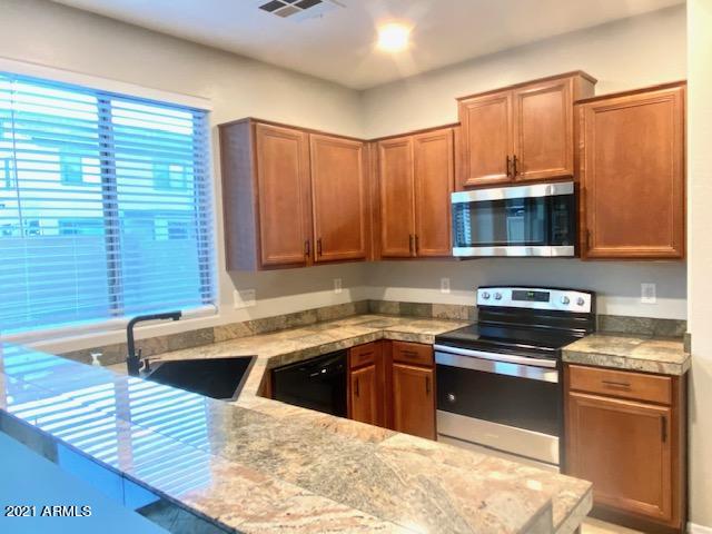 3657 East Hyatt Lane Gilbert, AZ 85295 - Photo 2 of 8 a kitchen with stainless steel appliances granite countertop a sink a stove a microwave cabinets and a window
