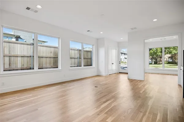 a view of an empty room with a window and a kitchen
