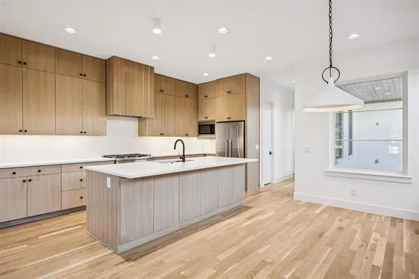 a large kitchen with cabinets wooden floor and a sink