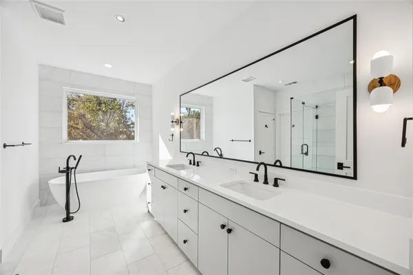 a bathroom with a double vanity sink mirror and bathtub