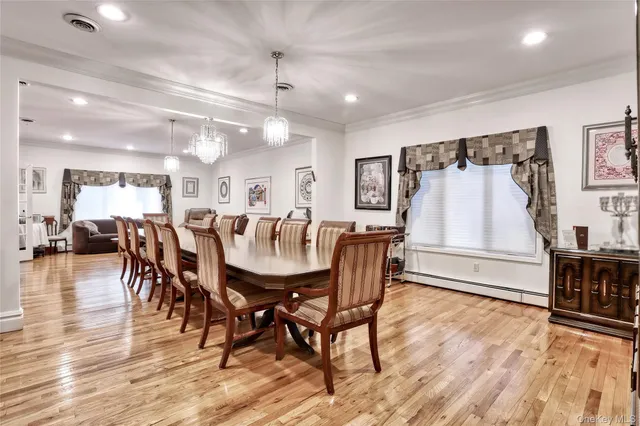 a dining room with wooden floor a chandelier a wooden table and chairs