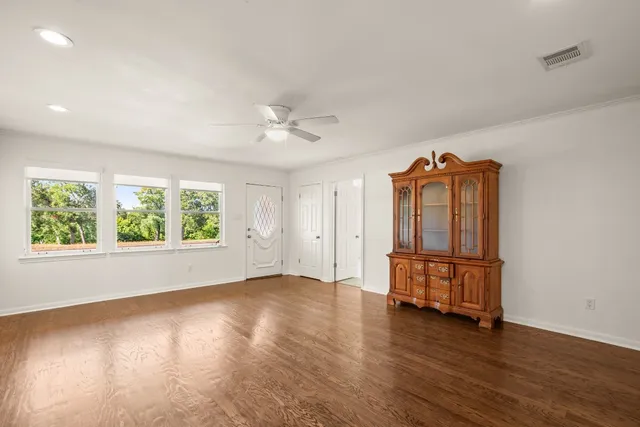 an empty room with wooden floor and windows