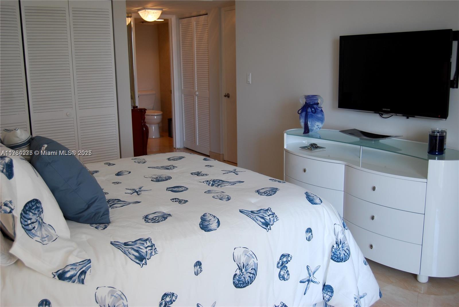 6423 Collins Avenue, Unit 901 Miami Beach, FL 33141 - Photo 12 of 17 a bedroom with a bed and a flat screen tv