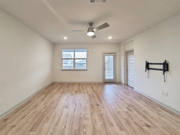 an empty room with wooden floor and windows
