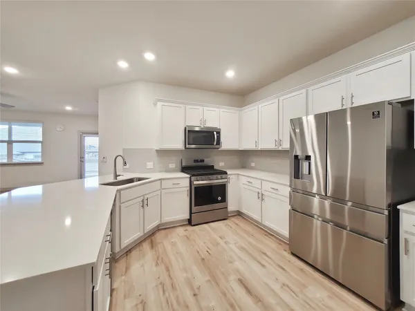 a kitchen with a refrigerator a stove top oven a sink and dishwasher with wooden floor