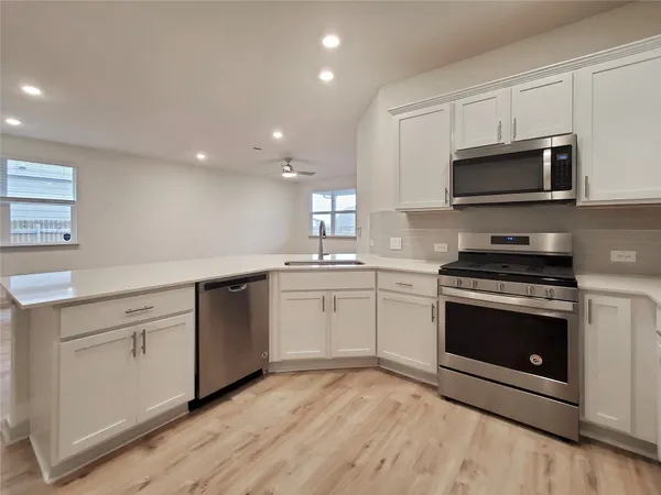 a kitchen with stainless steel appliances granite countertop a stove a sink and a microwave