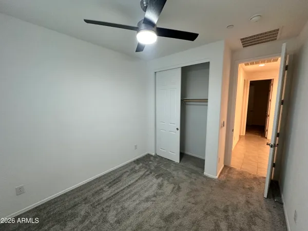 an empty room with closet and a chandelier fan