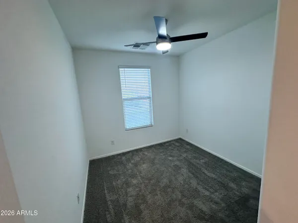 an empty room with a chandelier fan and windows