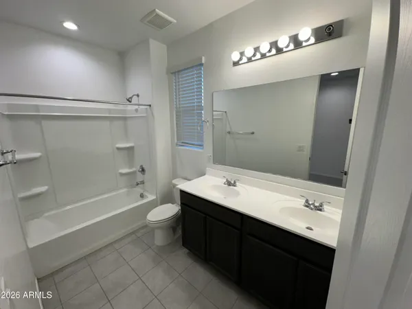 a bathroom with a double vanity sink and mirror with bathtub