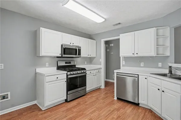 a kitchen with cabinets stainless steel appliances and wooden floor