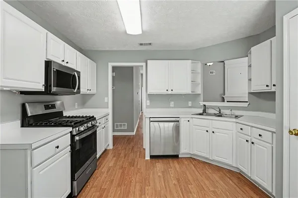a kitchen with granite countertop a sink cabinets and stainless steel appliances