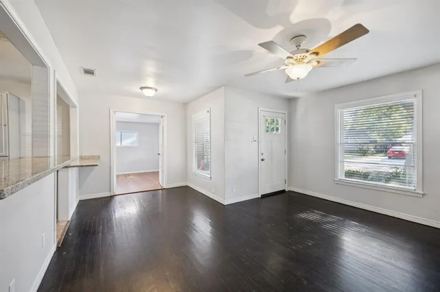 a view of an empty room with wooden floor and a window