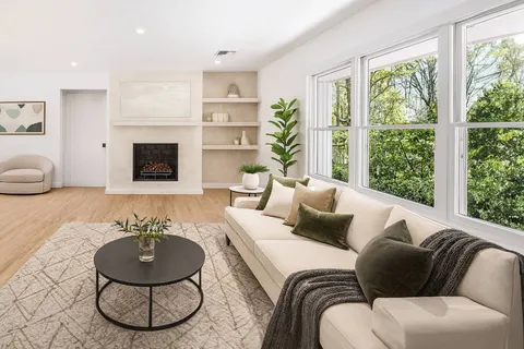 a living room with furniture a fireplace and a large window