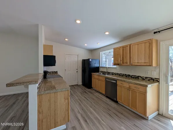 a kitchen with stainless steel appliances granite countertop a stove top oven a refrigerator a sink and dishwasher with wooden floor