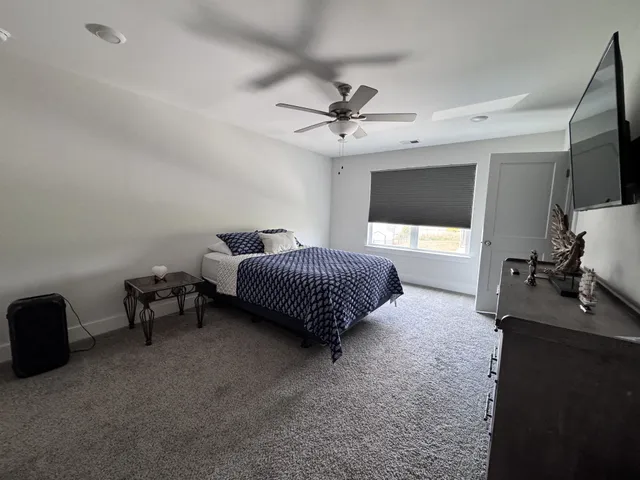 a spacious bedroom with a bed and a flat tv screen on dresser