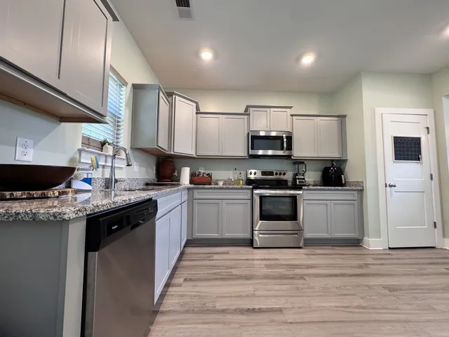 a kitchen with stainless steel appliances granite countertop a stove top oven a sink and a microwave