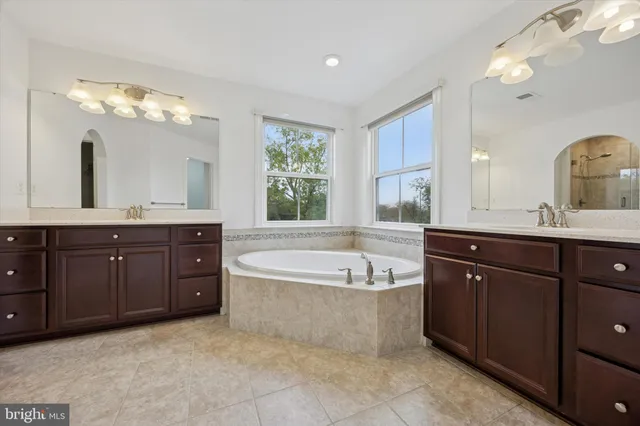 a spacious bathroom with a tub sink and mirror