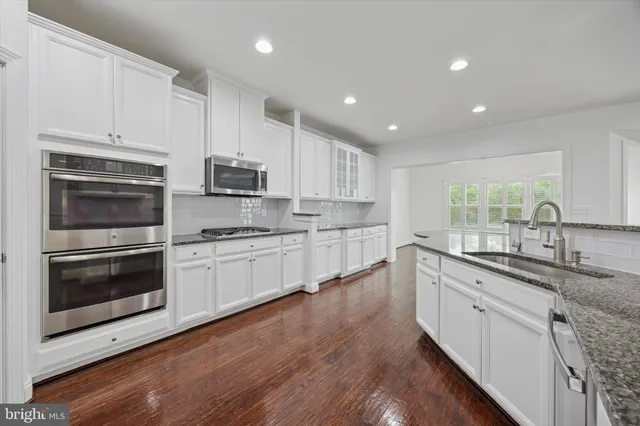 a kitchen with granite countertop white cabinets and stainless steel appliances