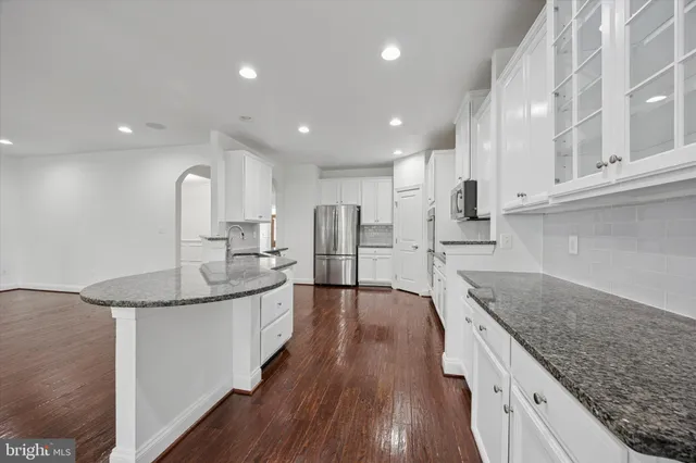 a large kitchen with stainless steel appliances granite countertop a lot of counter space and wooden floor
