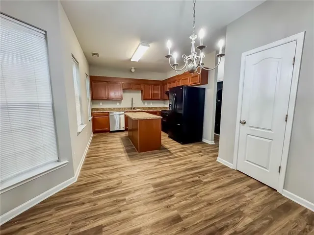 a kitchen with stainless steel appliances kitchen island granite countertop a refrigerator a sink dishwasher a stove and a dining table with wooden floor