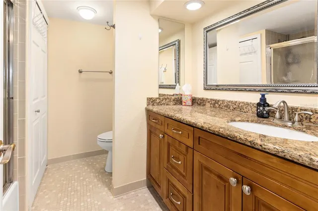 a bathroom with a granite countertop sink toilet and a mirror
