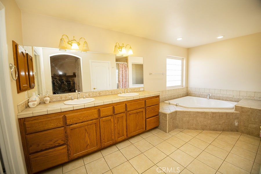 11830 Joshua Dell Road Victorville, CA 92392 - Photo 27 of 48 a spacious bathroom with a granite countertop sink and a mirror