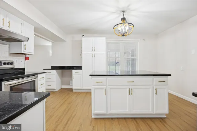 a kitchen with stainless steel appliances granite countertop white cabinets and wooden floor