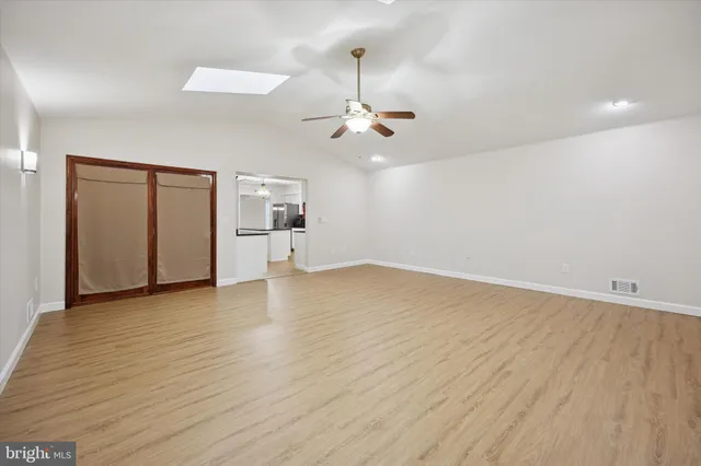 an empty room with wooden floor ceiling fan and windows