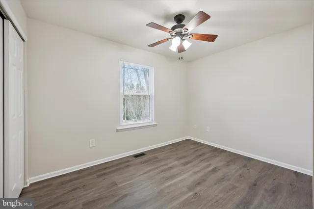 an empty room with wooden floor chandelier fan and window