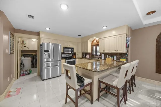 a kitchen with stainless steel appliances kitchen island granite countertop a refrigerator and a stove top oven