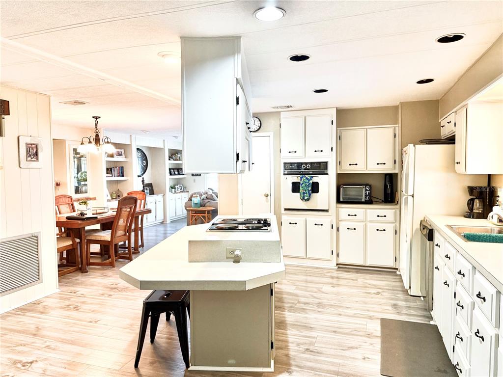 8010 Highpoint Boulevard Brooksville, FL 34613 - Photo 5 of 32 a kitchen with stainless steel appliances kitchen island granite countertop a table chairs sink and cabinets
