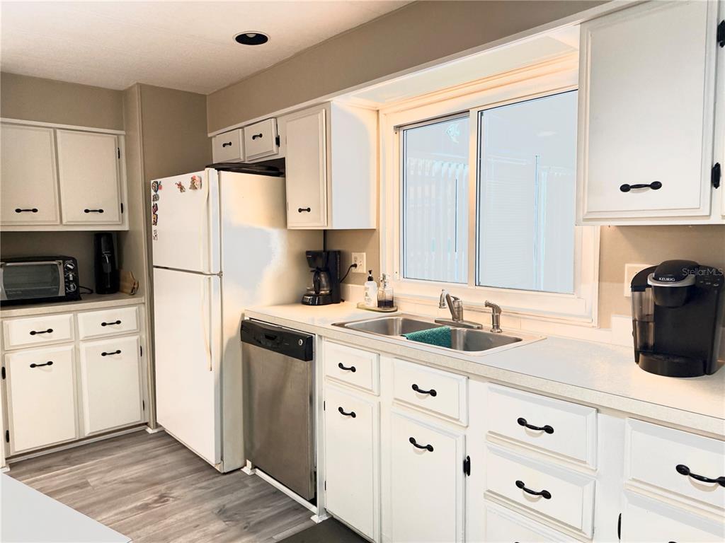 8010 Highpoint Boulevard Brooksville, FL 34613 - Photo 6 of 32 a kitchen with white cabinets and white appliances