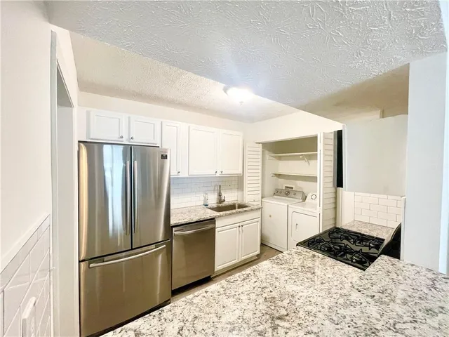 a kitchen with a refrigerator a stove a sink and dishwasher with wooden floor