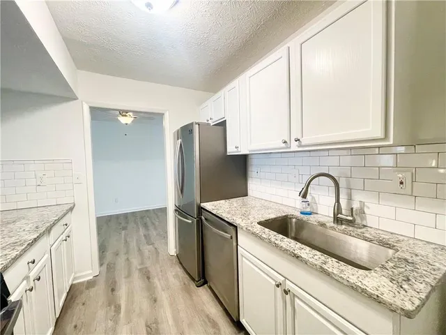 a kitchen with stainless steel appliances granite countertop a sink stove and refrigerator