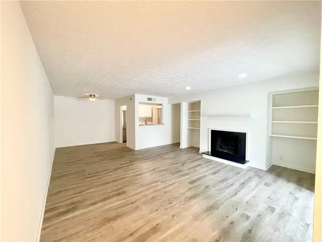 a view of empty room with wooden floor and fireplace