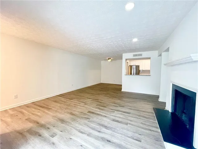 a view of empty room with wooden floor and fireplace