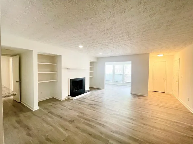a view of a livingroom with wooden floor and a fireplace
