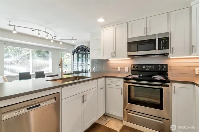 a kitchen with stainless steel appliances granite countertop a sink stove and microwave