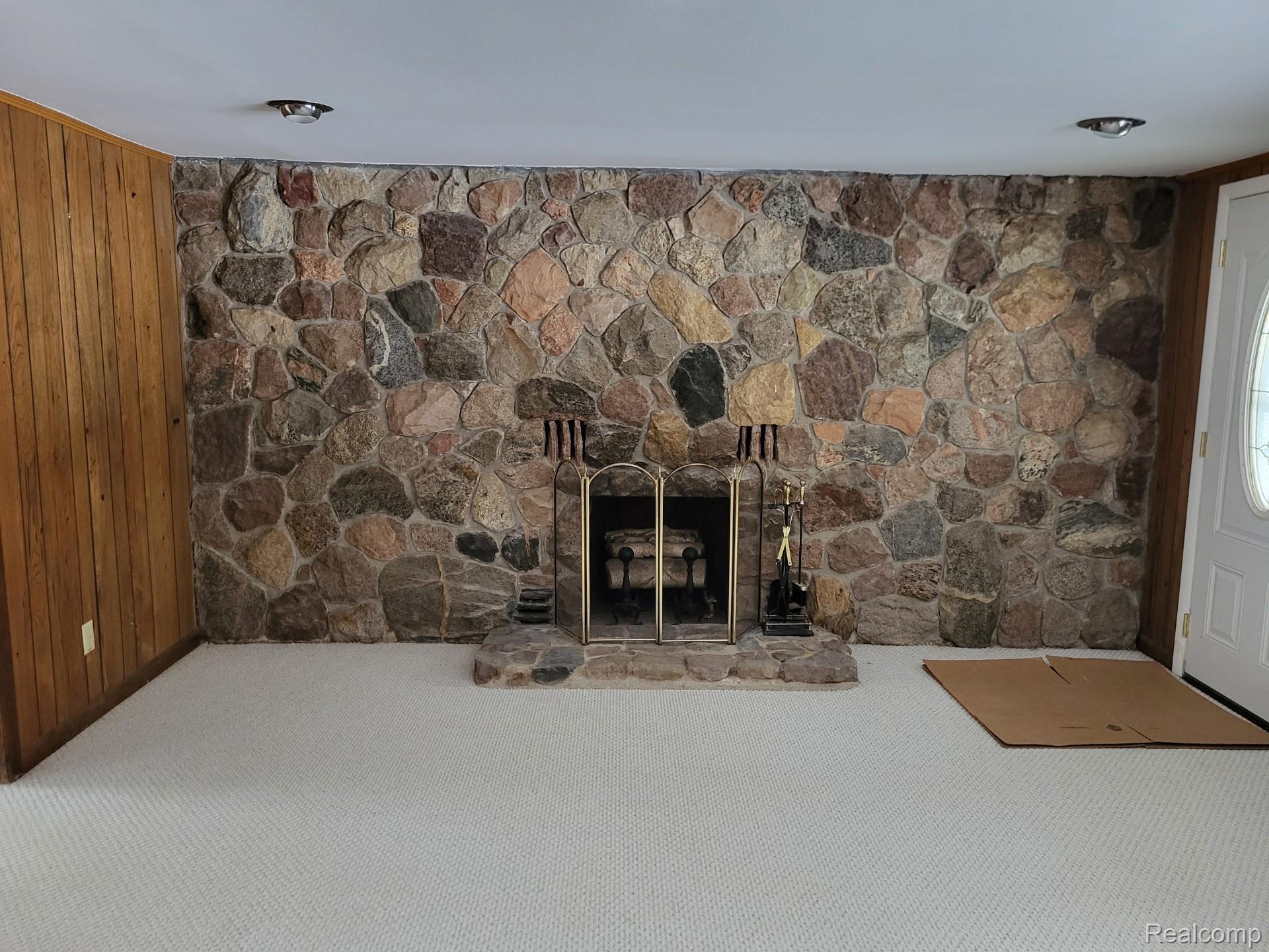 4662 North Lapeer Road Columbiaville, MI 48421 - Photo 10 of 19 Detailed view of carpet floors, wooden walls, and a stone fireplace