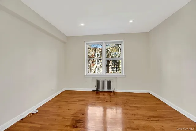 a view of empty room with window and wooden floor