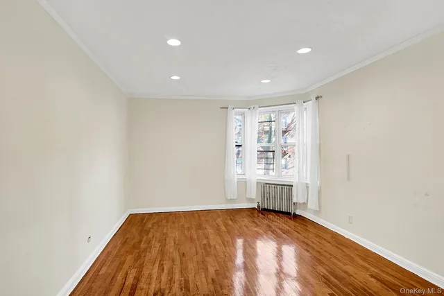a view of empty room with wooden floor and window
