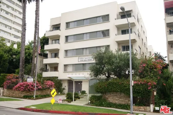 a front view of a multi story residential apartment building with yard and traffic signal