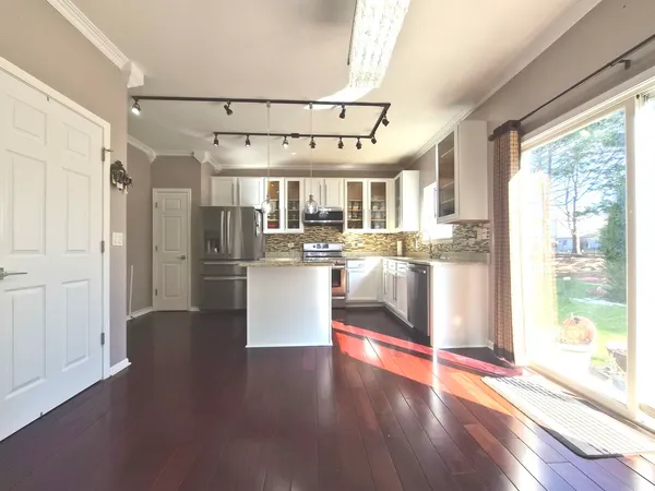 a kitchen with stainless steel appliances wooden floor and large window