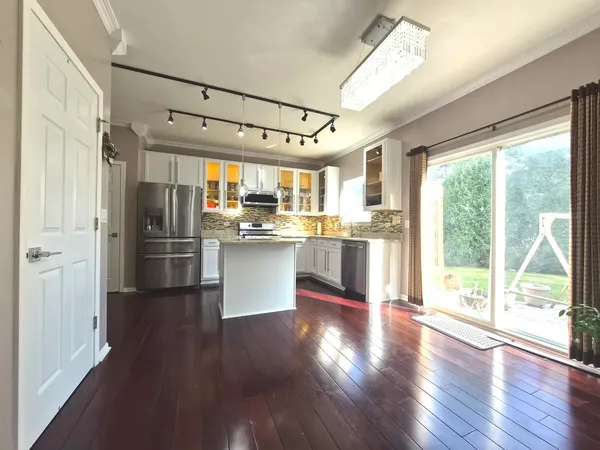 a kitchen with stainless steel appliances a refrigerator a sink dishwasher a stove and white cabinets with wooden floor