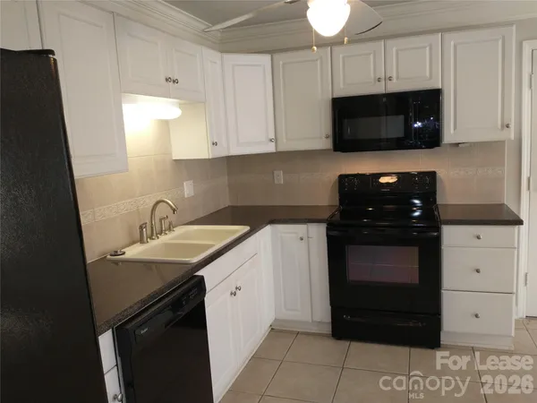 a kitchen with a sink and a stove top oven with white cabinets