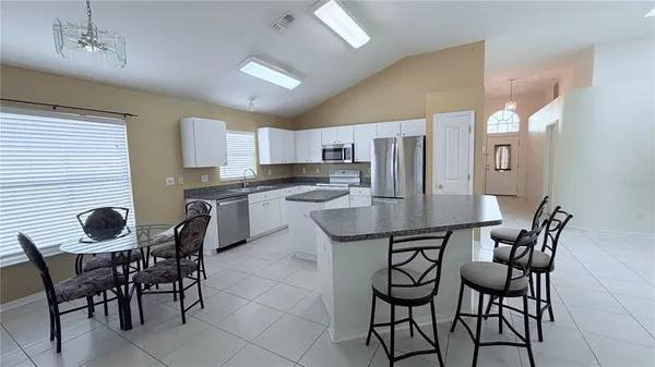 a kitchen with granite countertop stainless steel appliances a table and chairs in it