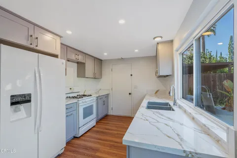 a kitchen with stainless steel appliances granite countertop a refrigerator a stove and a sink