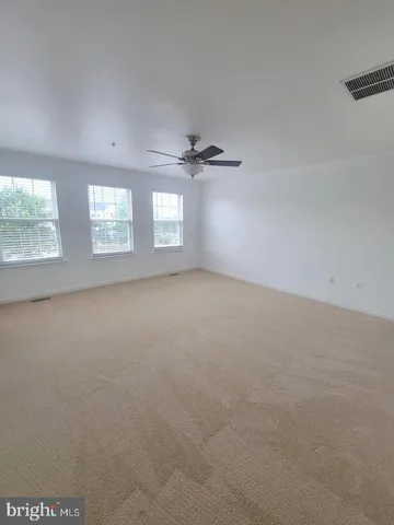 an empty room with chandelier fan and windows