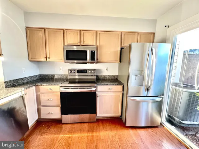 a kitchen with granite countertop a refrigerator stove and microwave