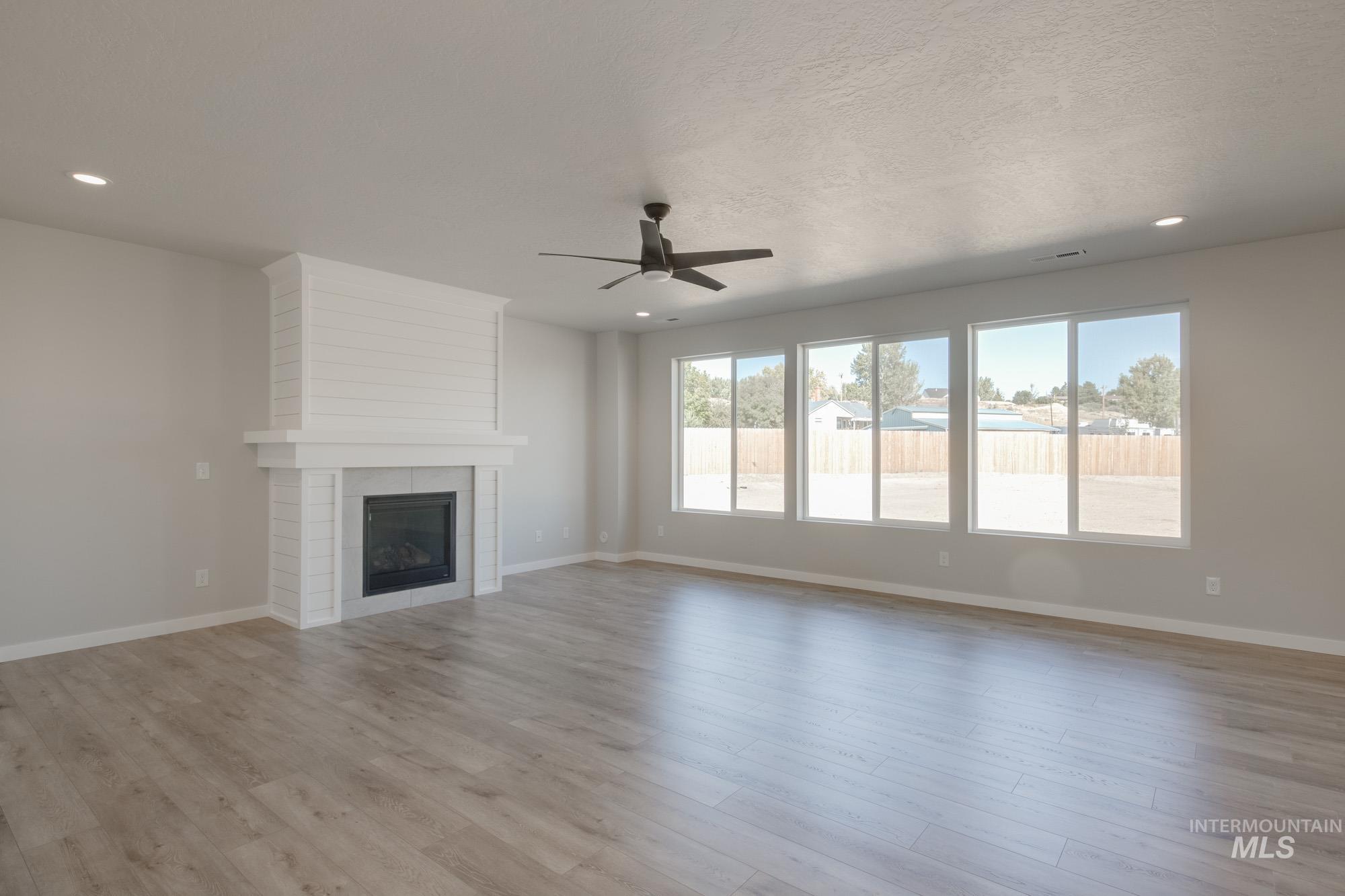13708 Judson Street Caldwell, ID 83607 - Photo 10 of 32 Unfurnished living room featuring recessed lighting, a tile fireplace, a ceiling fan, light wood-style floors, and a textured ceiling